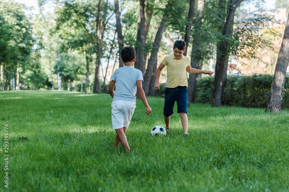 happy multicultural boys playing football on green grass happy multicultural boys playing football on green grass