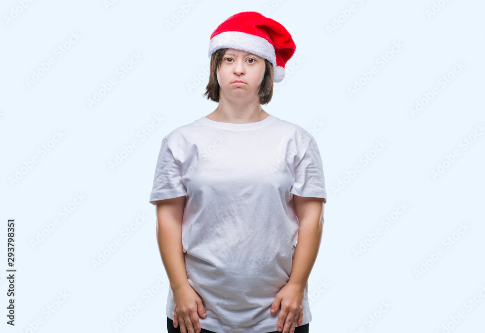 Young adult woman with down syndrome wearing christmas hat over isolated background with serious expression on face. Simple and natural looking at the camera. Young adult woman with down syndrome wearing christmas hat over isolated background with serious expression on face. Simple and natural looking at the camera.