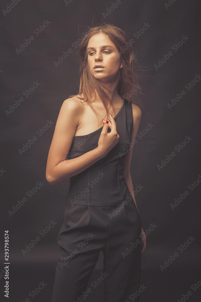 Naklejka premium Fashionable girl in golden gray tones in studio. Woman with unflappable face. Lifestyle concept in fashion world