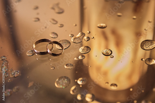 wedding rings on glass with drops