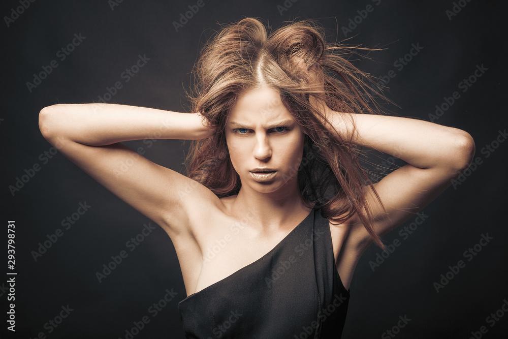 Fashionable girl in golden gray tones in studio. Woman with unflappable face. Lifestyle concept in fashion world. Female with flying hair Fashionable girl in golden gray tones in studio. Woman with unflappable face. Lifestyle concept in fashion world. Female with flying hair