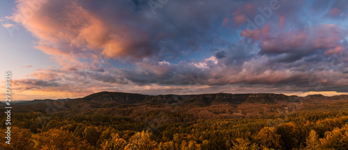 Autumn landscape at sunset - mountains  forests and beautiful clouds illuminated by the setting sun  hills of Bohemian Switzerland and Saxon Switzerland National Park  Czech Republic and Germany