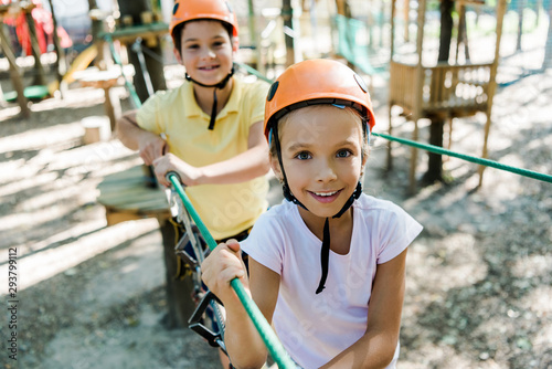 selective focus of adorable kid in helmet near friend with height equipment in adventure park