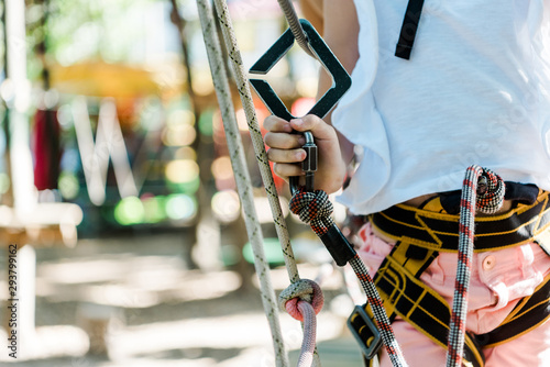 cropped view of kid with safety equipment in adventure park