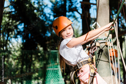 cheerful kid in helmet with height equipment in adventure park