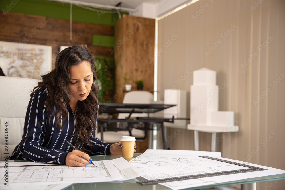 Young female architect working on blue print Young female architect working on blue print