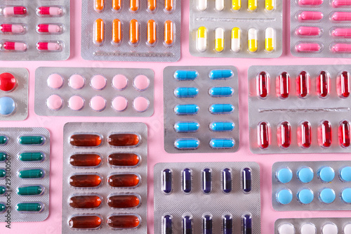 Flat lay composition with bunch of different colorful pills in blister packs. Pile of unpacked medication on paper textured background. Close up, copy space.