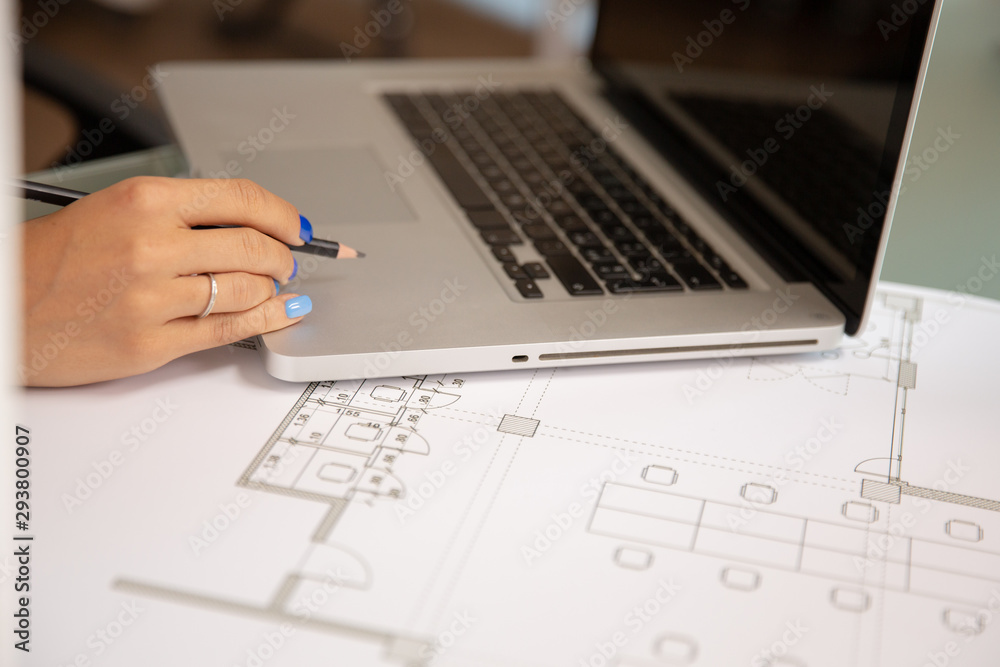 Close up shot of laptop over blueprints on the desk Close up shot of laptop over blueprints on the desk