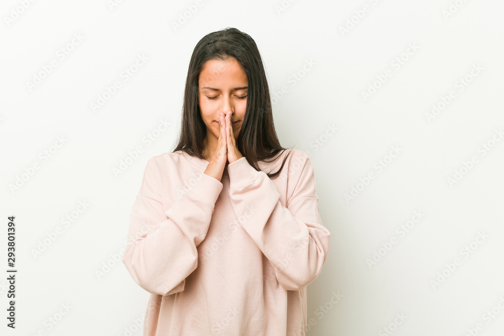 Young cute hispanic teenager woman holding hands in pray near mouth, feels confident. Young cute hispanic teenager woman holding hands in pray near mouth, feels confident.