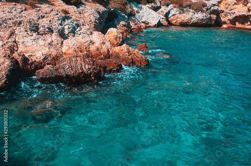 Sharp stones and rocks in the turquoise, blue sea. Brutal, orange-turquoise beautiful seascape. Aegean coast in Turkey. Bodrum.