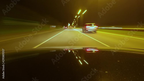 Driving a car in the night, with the street lights glowing and reflecting on the hood's surface. Timelapse, driver's POV.