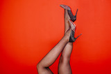 Female feet and pantyhose. Legs covered in black stockings or tights and red background