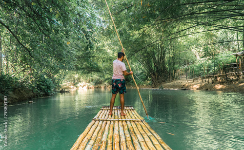 Man rowing bamboo raft, Martha Brae. Tourist boy whilst on cruise on vacation in Montego Bay, Jamaica, Caribbean.