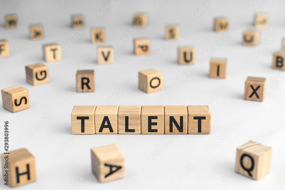 Talent - word from wooden blocks with letters, to be good at something aptitude or skill talent concept, random letters around, white  background