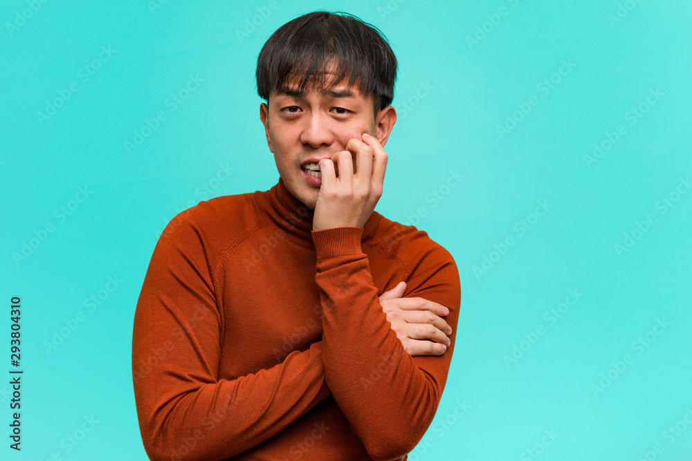 Young chinese man biting nails, nervous and very anxious Young chinese man biting nails, nervous and very anxious