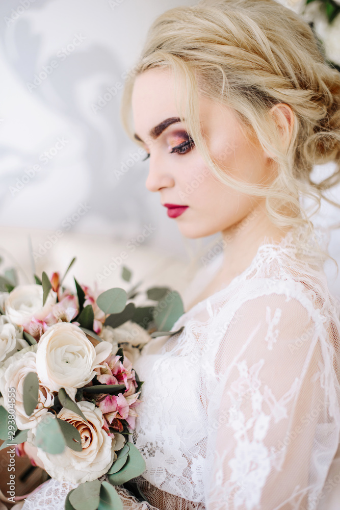 Naklejka premium The bride holds in hands a beautiful wedding bouquet. Portrait of an elegant bride with professional makeup and hairstyle in a luxurious wedding dress. Wedding details and accessories, rustic wedding