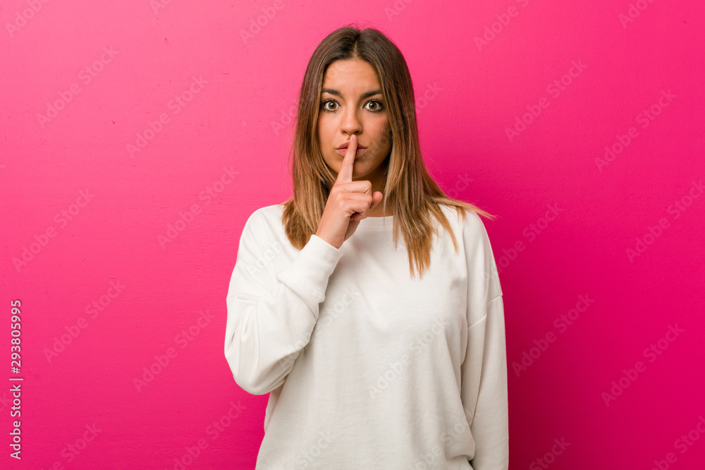 Young authentic charismatic real people woman against a wall keeping a secret or asking for silence. Young authentic charismatic real people woman against a wall keeping a secret or asking for silence.