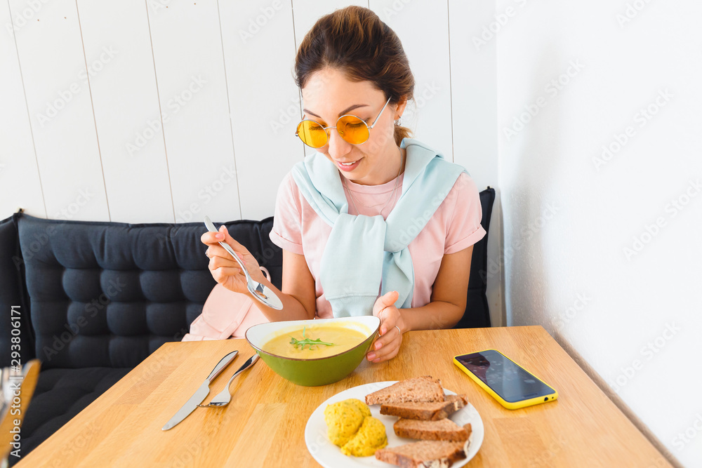 Asian Girl eating yellow vegetarian soup mashed pumpkin. Concept of vegetarian and vegan cuisine Asian Girl eating yellow vegetarian soup mashed pumpkin. Concept of vegetarian and vegan cuisine