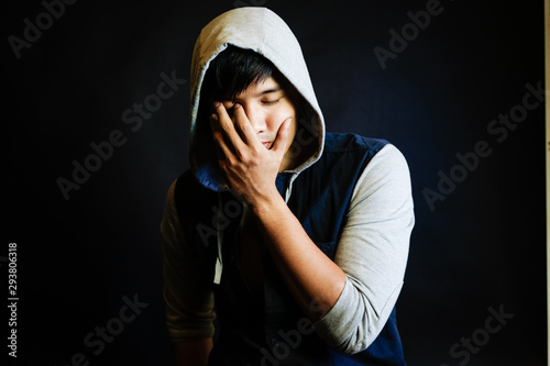 Portrait of a sad young man with hand cover his face and eye close in the studio.
