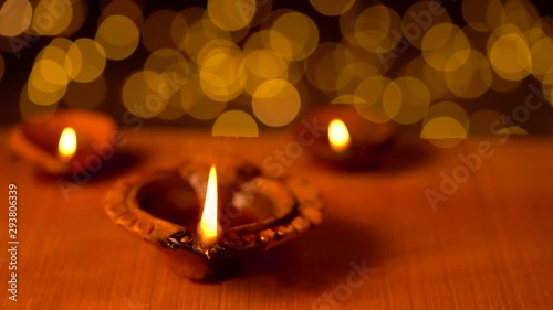 Decorative Diya Oil Lamps For Religious Tradition. Diya or clay lamps on Diwali night with beautiful bokeh background on a wooden surface with copy space. Video footage of traditional clay oil lamps.
