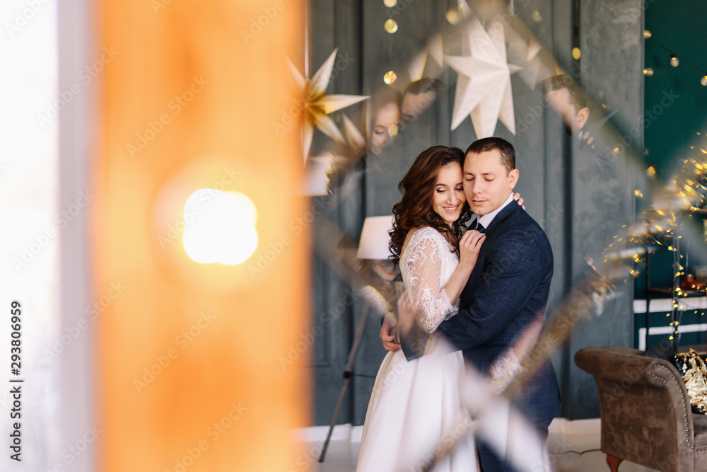 Obraz premium Winter wedding. Wedding couple portrait of the bride and groom. Wedding bouquet in the hands of the bride. Photoshoot on the background of a Christmas tree with a blurred background and bokeh