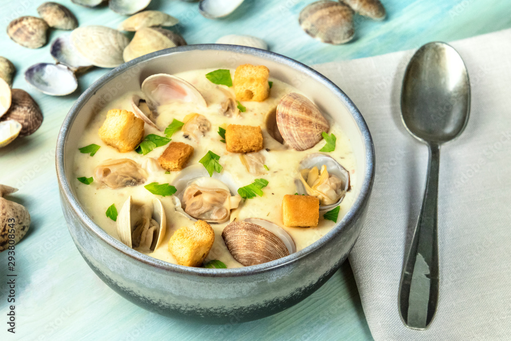 Clam chowder with fresh parsley and croutons, with shells on a blue background