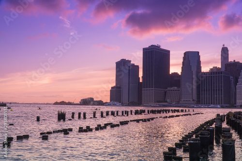 Beautiful view of downtown Manhattan skyline financial district as sun goes down in majestic sunset behind city cast purple color across evening sky