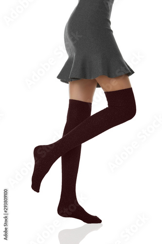 Medium bottom shot of a female figure in the gray bell-shaped skirt and maroon shadow-proof stockings with lurex. The girl on tiptoe is posing on the white background.  photo