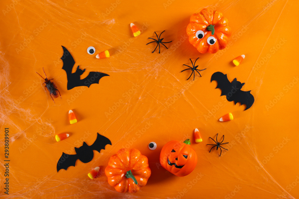 Halloween themed flat lay composition with decorative jack-o-lantern pumpkins, on paper textured background with a lot of space for text. Close up, top view. Halloween themed flat lay composition with decorative jack-o-lantern pumpkins, on paper textured background with a lot of space for text. Close up, top view.