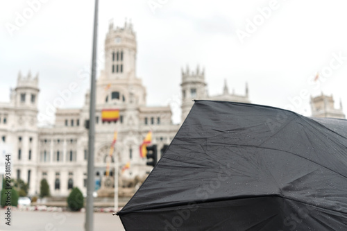 umbrella with famous building visiting madrid in a rainy day.