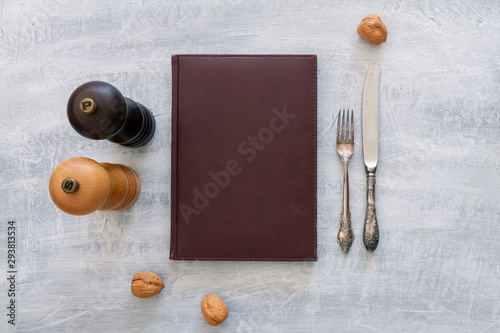 Vintage leather menu with rustic steel or metal silverware with copy space. Top view or above view composition