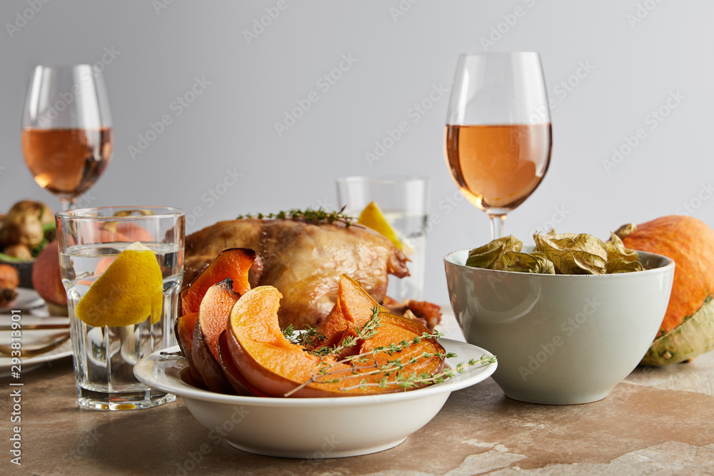 festive thanksgiving day with baked pumpkin, grilled turkey and glasses with rose wine and lemon water isolated on grey festive thanksgiving day with baked pumpkin, grilled turkey and glasses with rose wine and lemon water isolated on grey
