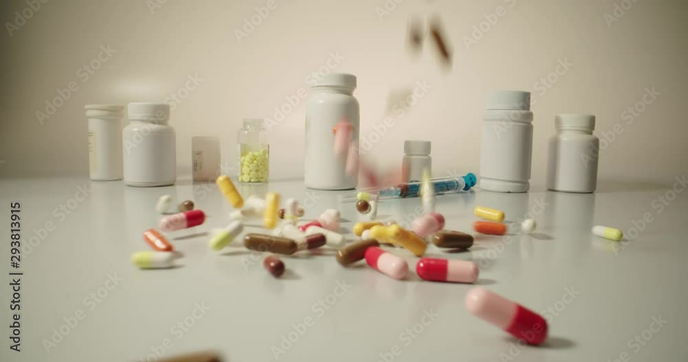 Closeup shot of different pills falling on table with tablets cans and syringes - mosern drug and pharmacy addiction, pharmaceutical industry concept 4k footage Closeup shot of different pills falling on table with tablets cans and syringes - mosern drug and pharmacy addiction, pharmaceutical industry concept 4k footage