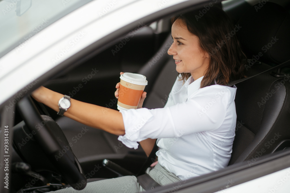 Young woman in car drinking coffee