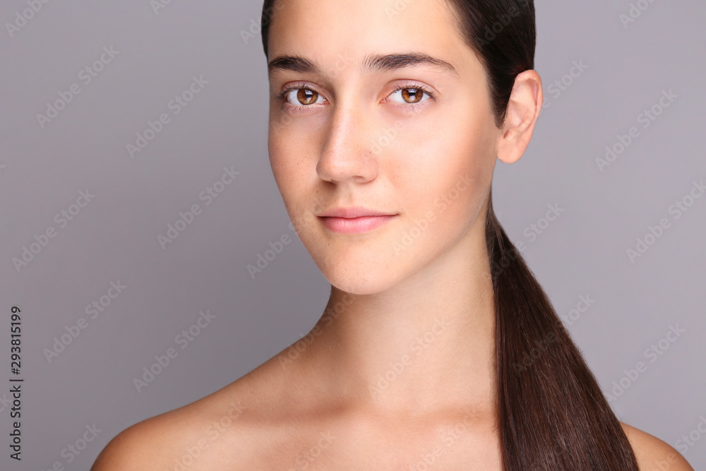 Portrait of young beautiful woman with perfectly clean face skin. Female with long black hair tied in ponytail smiling wide showing skincare results. Close up, copy space background. Portrait of young beautiful woman with perfectly clean face skin. Female with long black hair tied in ponytail smiling wide showing skincare results. Close up, copy space background.