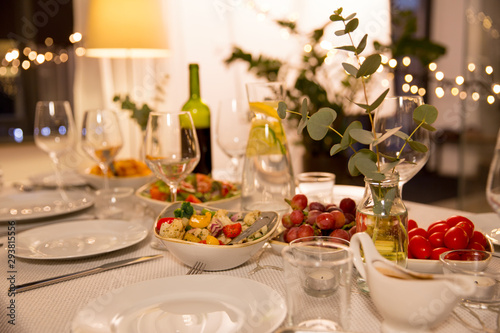 celebration, holidays, catering and eating concept - table served with plates, wine glasses and food for home dinner party