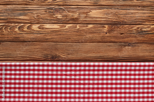 top view of red checkered napkin on wooden brown table