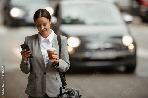 Young businesswoman drinking coffee and using phone