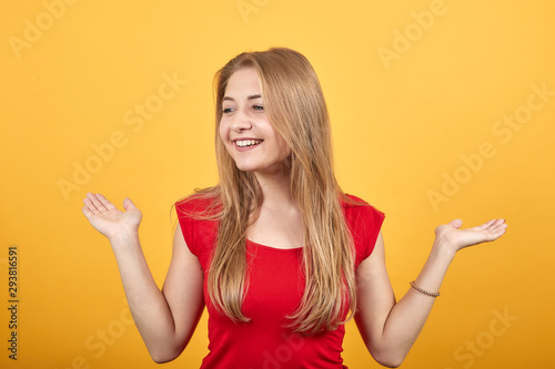 young blonde girl in red t-shirt over isolated orange background shows emotions