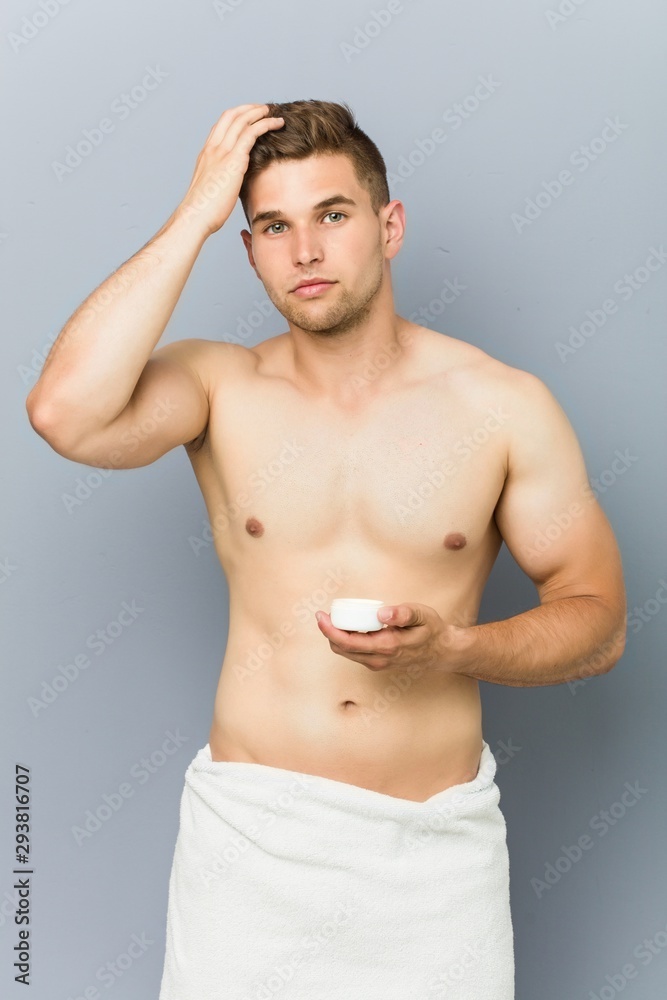 Fototapeta premium Young handsome man using hair wax