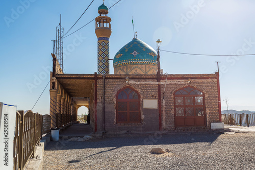 A mosque Prophet Khidr or Khezr Temple with a blue mosaic dome and a minaret on top of a mountain, on the outskirts of Qom, Iran. Place in the middle of the desert under blue sky and scorching sun. photo