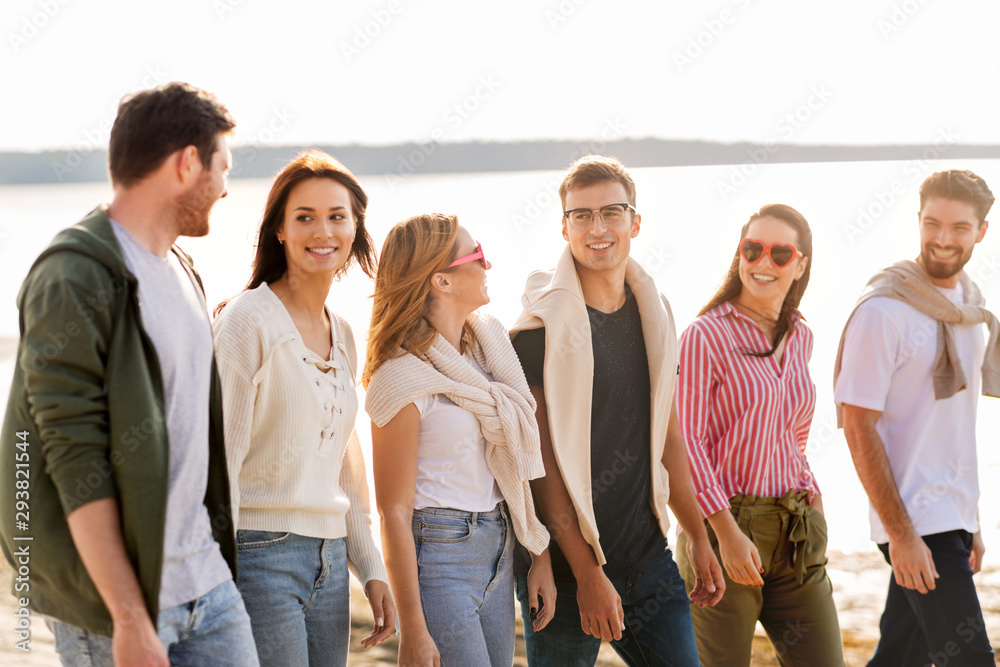 Obraz premium friendship, leisure and people concept - group of happy friends walking along beach in summer