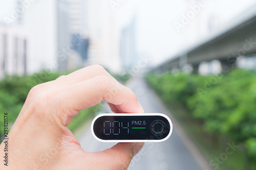 Closeup hand holding air quality monitor to detect level of pollution or small particulate (PM 2.5) in the city and it's show very low with green light, which mean air quality is good and safe. AQI.