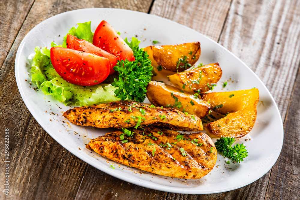 Grilled chicken fillet and vegetableson white plate Grilled chicken fillet and vegetableson white plate