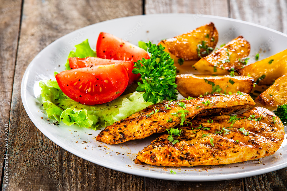 Grilled chicken fillet and vegetableson white plate Grilled chicken fillet and vegetableson white plate