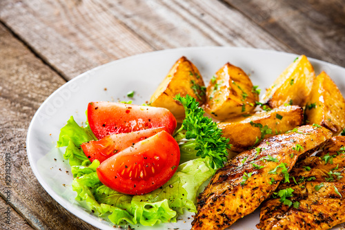 Grilled chicken fillet and vegetableson white plate photo