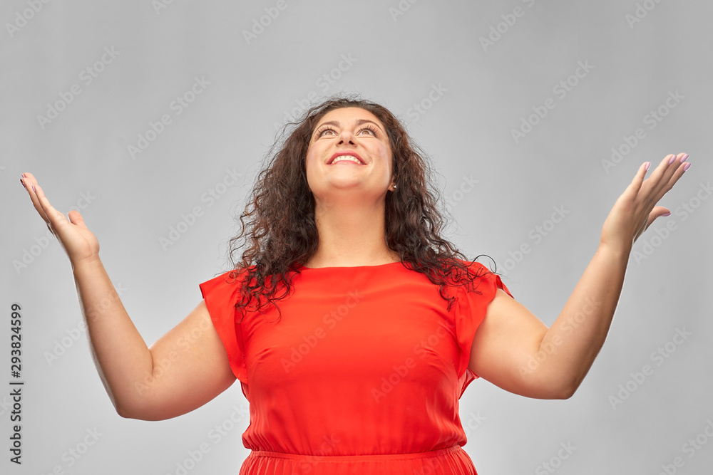 people and emotion concept - happy amazed woman in red dress looking up over grey background
