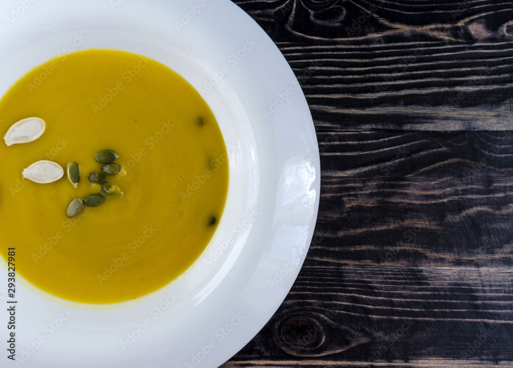 pumpkin soup in white plate natural wood dark background top view pumpkin soup in white plate natural wood dark background top view