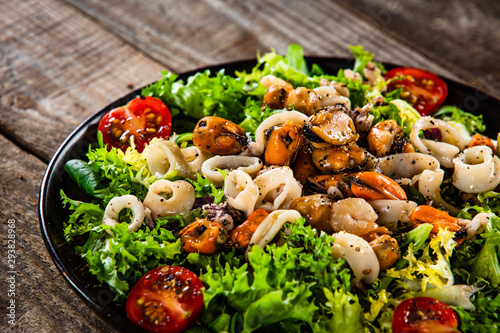 Salad with seafood and vegetables on wooden table