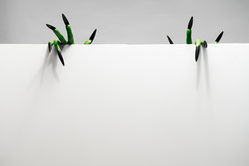 Two green hands with long nails holds empty sheet in studio, place for inscription